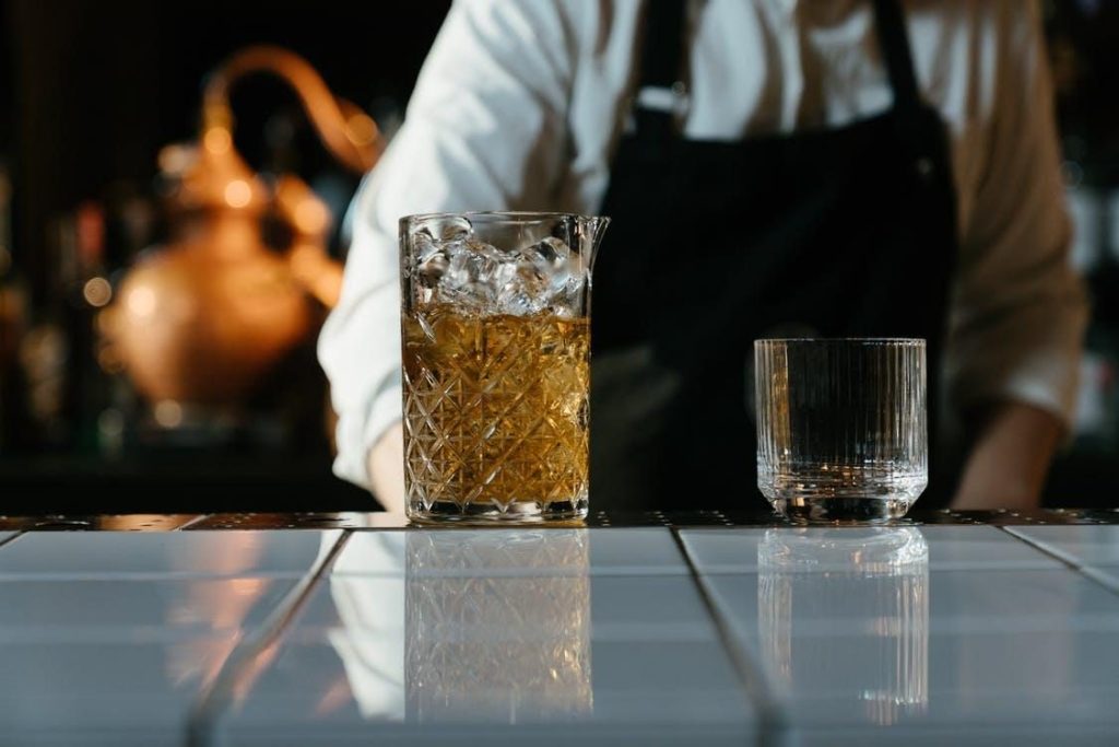 A Drink on the Rocks Placed on a Bar Beside an Empty Glass