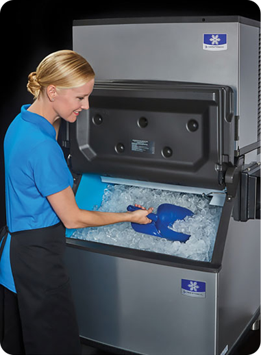 A large ice machine with a woman scooping out ice.