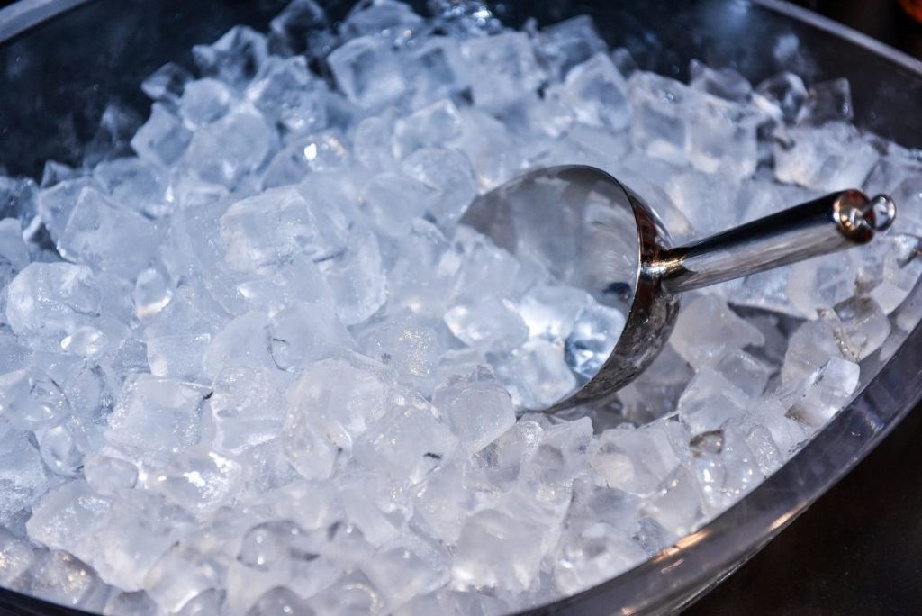 A metal ice scooper in a bucket of ice.